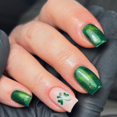 Close-up of a hand with green glittery nail polish on a dark background