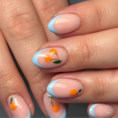 Close-up of a hand with nail art featuring small orange flowers and green leaves on a light blue background.