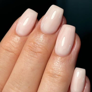 Close-up of a hand with light pink nail polish on a dark background