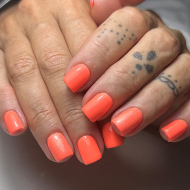 Close-up of hands with bright orange nail polish on a neutral background
