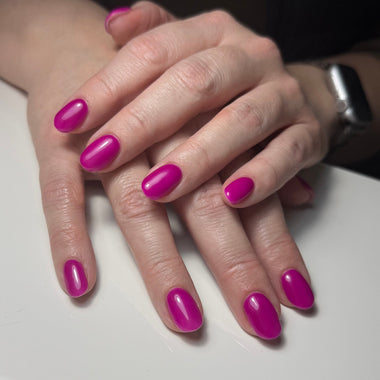 Close-up of hands with bright pink nail polish on a neutral background