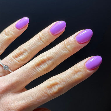 Hand with purple nail polish on a black background
