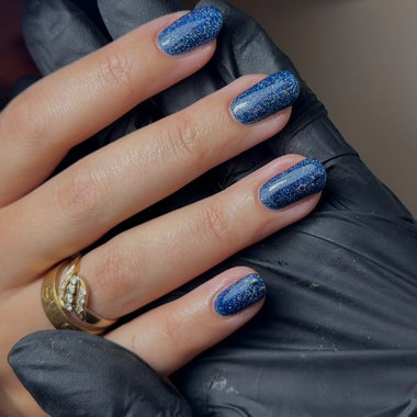 Hand with blue glittery nail polish wearing a black glove