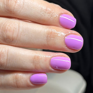 Close-up of a hand with purple nail polish on a blurred background
