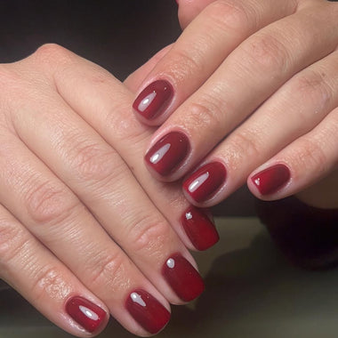 Close-up of hands with red nail polish on a neutral background