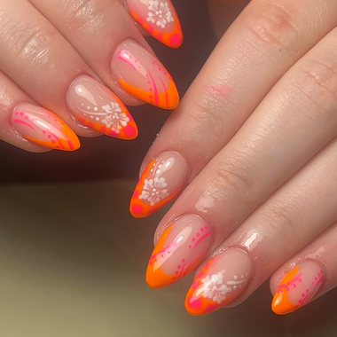 Close-up of hands with orange and pink nail polish on a neutral background