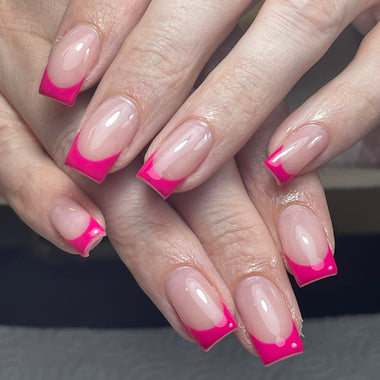 Close-up of hands with pink and white gradient nail design on a dark background