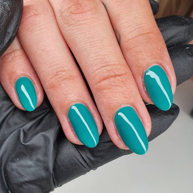 Hand with teal nail polish wearing a black glove on a neutral background