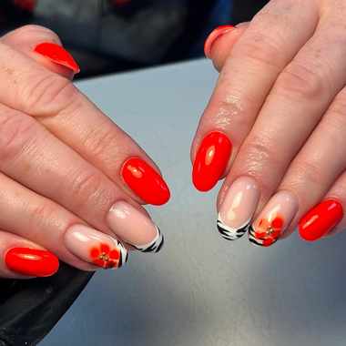 Close-up of hands with red nail polish and black and white floral designs on a neutral background  HGP Red hot