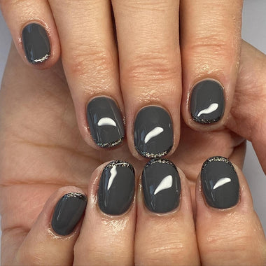 Close-up of a hand with black nail polish and white crescent moon designs on a neutral background