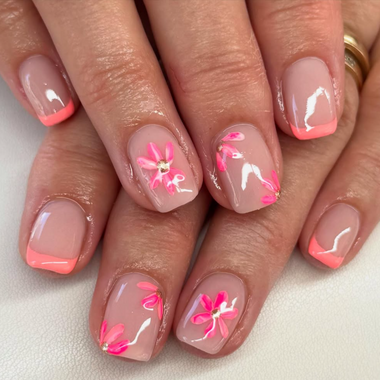 Close-up of hands with pink floral nail art on a neutral background