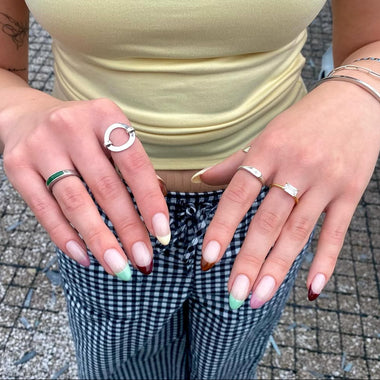 Close-up of hands with painted nails and rings on a textured surface