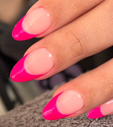 Close-up of a hand with pink and white nail polish on a blurred background