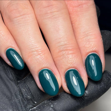 Close-up of a hand with teal nail polish on a dark background - halo gel polish harmony