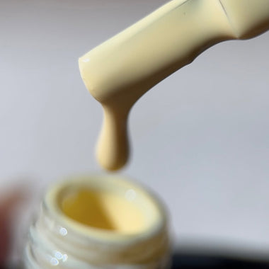 Close-up of a dropper dispensing yellow liquid into a small container.