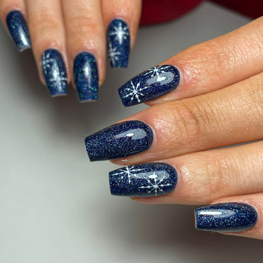 Nail art with blue glitter and star designs on a neutral background