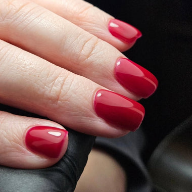 Close-up of a hand with red nail polish on a dark background