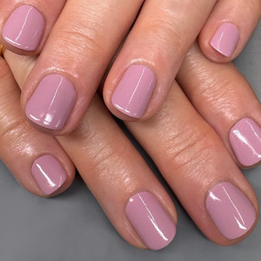 Close-up of hands with pink nail polish on a gray background