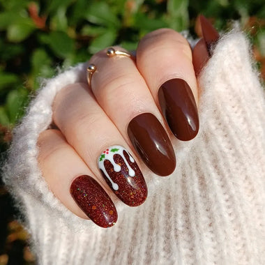 Close-up of a hand with brown nail polish and a decorative nail, wearing a white textured garment.