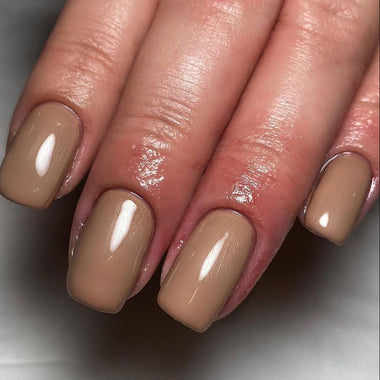 Close-up of a hand with beige nail polish on a neutral background