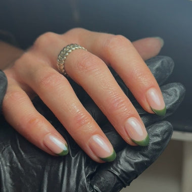 Hand with green and white nail polish wearing a black leather glove.