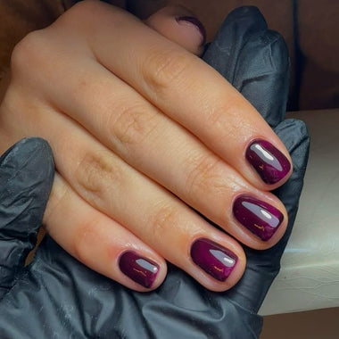Hand with dark purple nail polish wearing a black glove
