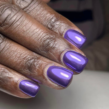 Close-up of a hand with purple nail polish on a neutral background