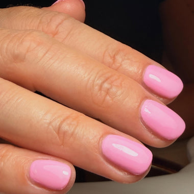 Close-up of a hand with pink nail polish on a neutral background
