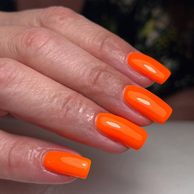 Close-up of a hand with bright orange nail polish on a neutral background
