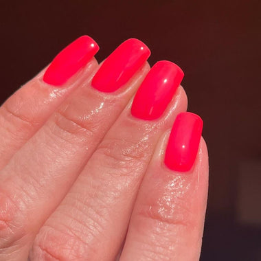 Hand with bright pink nail polish on a blurred background