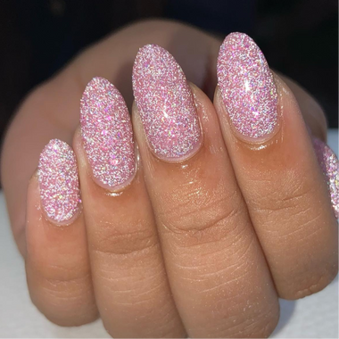 Close-up of a hand with pink glittery nail polish on a neutral background