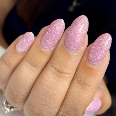 Close-up of a hand with pink glittery nails against a dark background
