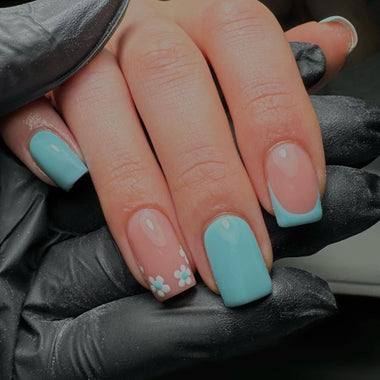 Hand with light blue and pink nail design on a dark background