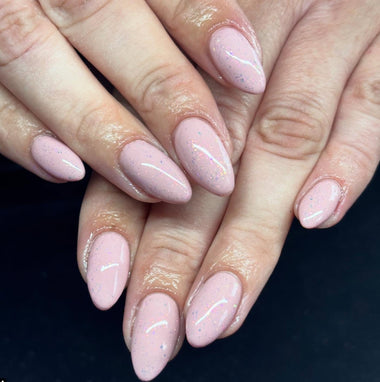 Close-up of hands with pink nail polish on a dark background