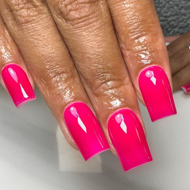 Close-up of a hand with bright pink nails on a neutral background
