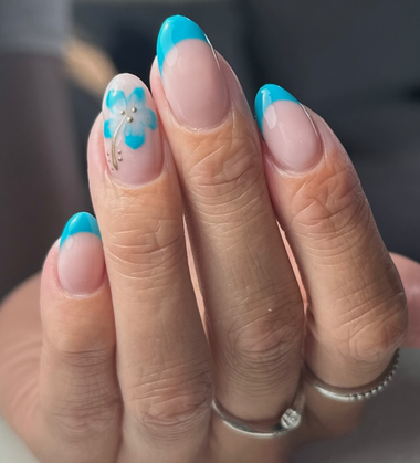 Hand with blue nail polish and floral design on a blurred background