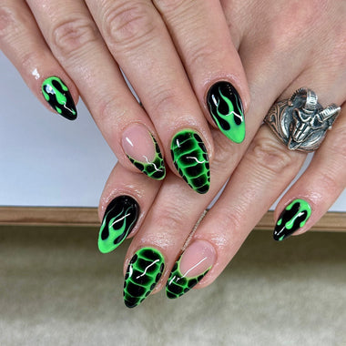 Nails with green and black flame design on a neutral background