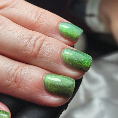 Close-up of a hand with green nail polish on a blurred background