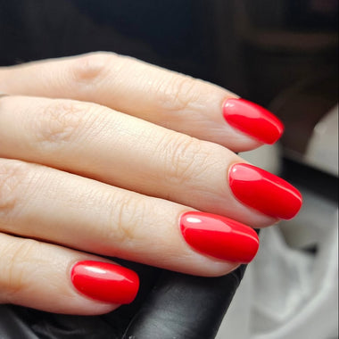 Hand with red nail polish wearing a silver ring on a blurred background