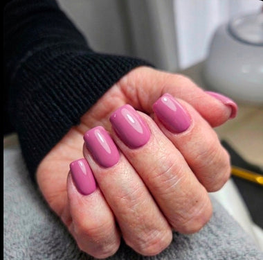 Hand with pink nail polish on a neutral background
