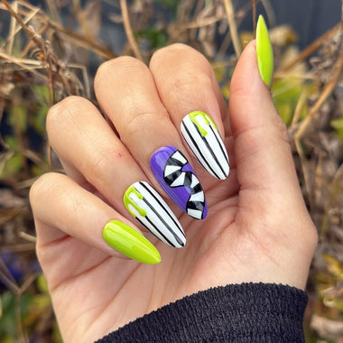 Hand with colorful nail art against a natural background
