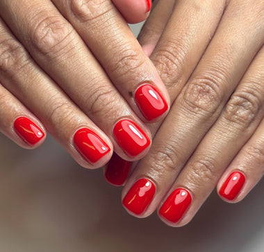 Close-up of two hands with red nail polish on a neutral background