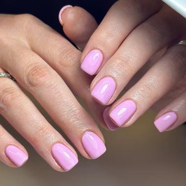Close-up of hands with pink nail polish on a blurred background
