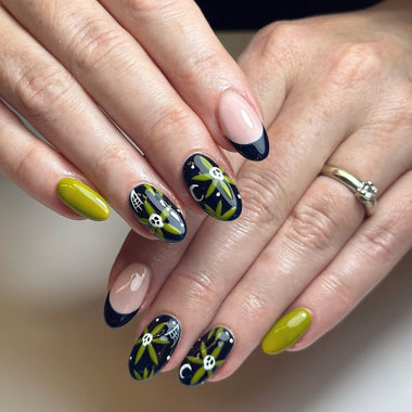 Close-up of hands with decorative nail art featuring green, black, and white designs.