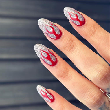 Nails with red and silver flame design on a blurred background