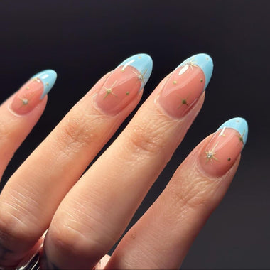 Nails with a gradient design from pink to blue on a dark background