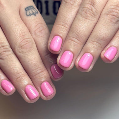 Close-up of hands with pink nail polish on a neutral background