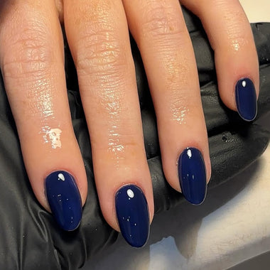 Close-up of a hand with blue nail polish on a dark background
