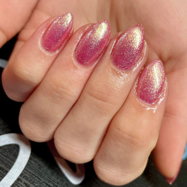 Close-up of a hand with pink glittery nail polish on a blurred background