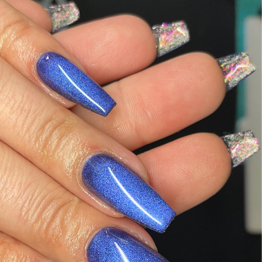 Close-up of a hand with blue glittery nails against a blurred background